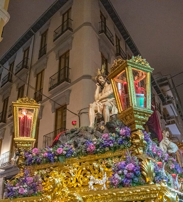 Granada during Holy Week Procession with a Christ figure adorned with purple flowers