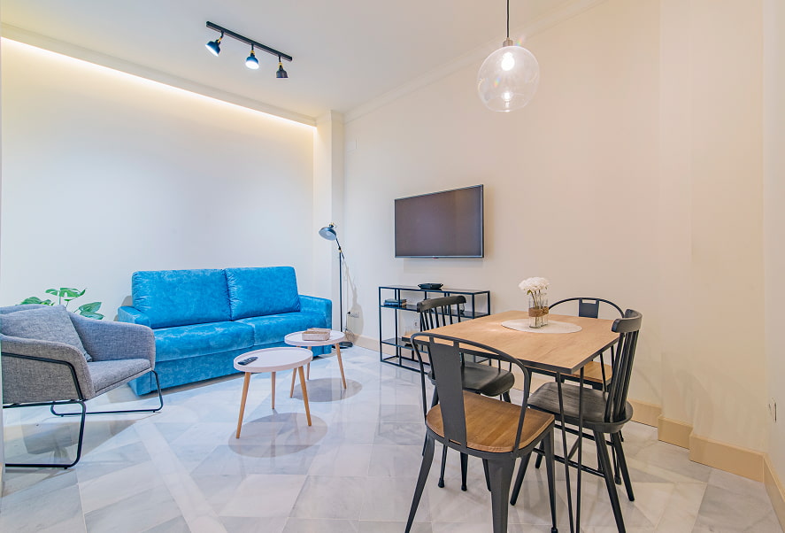 Apartamento Twin Standard 4 Zona de estar, con sofá azul, muebles de diseño y TV de pantalla plana