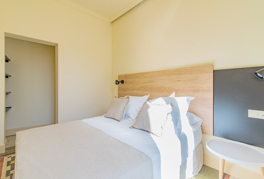 Apartamento Standard 9 Vista lateral de la habitación con cama doble y cabecero de madera